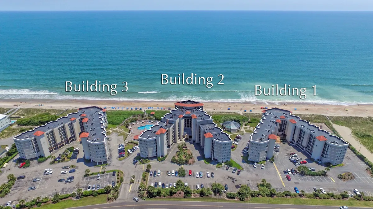 This exterior image features the resort’s architecture, a sparkling pool area, and a sweeping ocean view. The inviting pool is surrounded by sunbathing spots, with the ocean just beyond, reinforcing the idea of resort-style amenities and year-round aquatic enjoyment. The scene speaks to both relaxation by the water and the beauty of the beachside location.