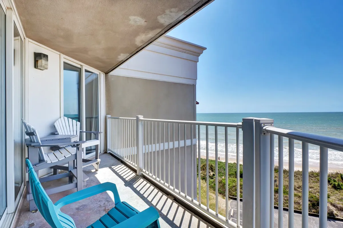 A peaceful private balcony overlooking the vast ocean, furnished with comfortable outdoor seating. The top-floor vantage point offers unobstructed vistas, perfect for sunrise coffees or evening relaxation as described in the section.